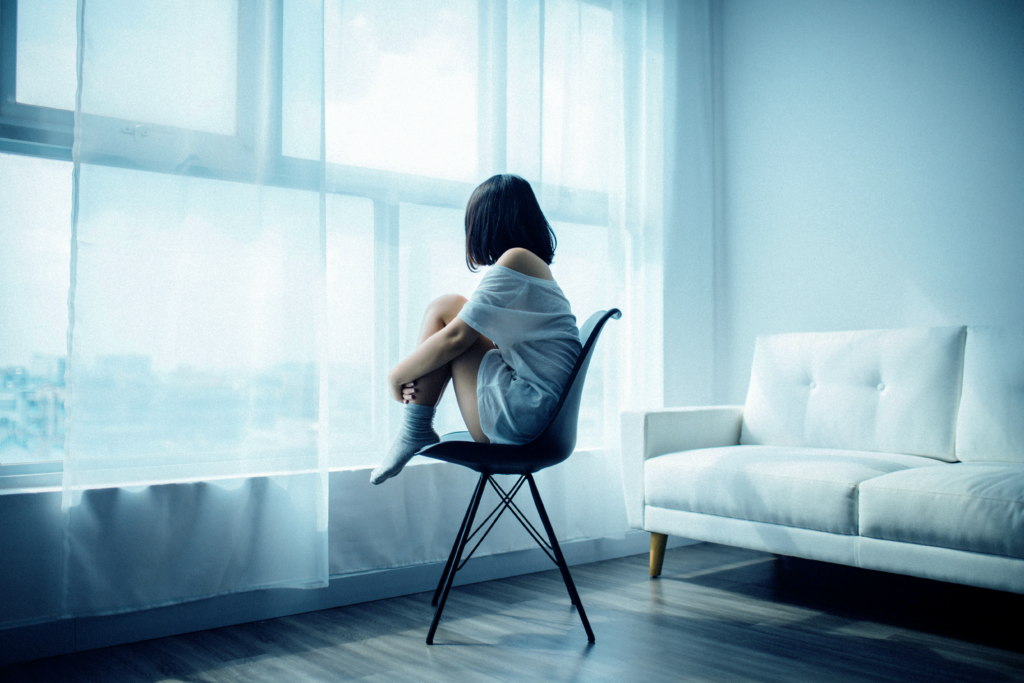 Arrivo_Depression_image Woman sitting on a chair looking at the window